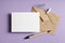 Stationary greeting card mockup with envelope, pen and dry flower twig on lavender color background