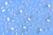 Stationery chaotically scattered on a blue background. White paper clips, clerical buttons and small pink stars in the