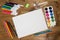 Stationery for children`s creativity on wood background. Sketchbook, colored pencils, paints, felt tips, brushes for drawing. Cop