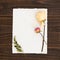 Stationery Paper with Pretty Dried Roses in Cream and pink with leaves.  The page is white and on rustick dark wood boards backgro