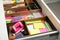 Stationery and sewing accessories in open desk drawer, closeup