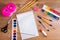 Stationery on a wooden table. Notebook, pens, pencils, paints, scissors, paper clips, eraser, pencil sharpener, glue and brush on