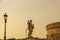 Statue angel on the bridge over the Tiber, near the Saint Angel Castle. Beautiful evening golden sunset at Saint Angel Castle.