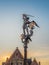 Statue of Archangel Saint Michael slaying a dragon next to promenade of river Lys in Ghent, Belgium and at dusk.