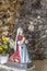 Statue of Bernadette praying to Our Lady of Lourdes with flowers next to her
