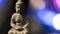 Statue of the Buddha of Serenity, on a black background surrounded by luminous circles