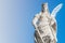 Statue of Catherin with writing bird feather, sword and cartwheel at ancient portal in Magdeburg, Germany, closeup, gradient blue