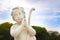 Statue of a cherub praying against blue sky