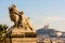 A statue of child and lion in Marseille, France, with Notre-Dame de la Garde basilica in the distance