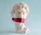 Statue of  David  head  with red ribbon on mouth on  blue background. Minimal art poster