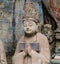 Statue of disciple or follower in front of giant Buddha at Dazu Rock Carvings