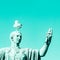 Statue of emperor with gull on the head. Man taking selfie. Humor concept. Mint color background