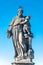 Statue of fat and big priest with a child at the Charles Bridge in Prague at blue sky, Czech Republic, summer time