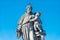 Statue of fat and big priest with a child at the Charles Bridge in Prague at blue sky, Czech Republic, summer time