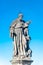 Statue of fat and big priest with a child at the Charles Bridge in Prague at blue sky, Czech Republic, summer time