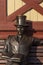 Statue of gentleman on bench in vintage frock coat, top hat and dandy mustache