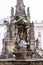 Statue of Hercules standing on a fountain in Olomouc in winter. In the background, the column of the Holy Trinity