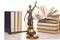 Statue of justice, judge`s hammer behind books on a white background