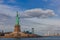 Statue of Liberty overlooking buildings of Jersey City and Manhattan by water, in New York City, USA