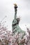 Statue of Liberty in Tokyo on the island of Odaiba in blooming sakura on a gloomy day.