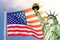 Statue of Liberty wearing a surgical mask, US american flag background. New coronavirus, covid-19 in New York and USA