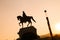 Statue of a man on a horse in dynamic composition, sunset and co