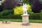 Statue of a man and a woman on a plinth and a seat in a garden