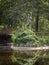 Statue of Poseidon with reflection immersed in Nature and Vegetation in front of a Small Lake