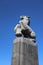 A statue of a prancing horse with a little girl between the front legs on a high, wide pillar by sculptor Hildo Krop