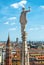 Statue on spire of Milan Cathedral on blue sky background, Milan, Italy. Detail of roof overlooking Milano city in summer