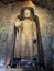 Statue of standing Buddha in monk clothes carved in cave