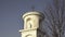 Statue of Virgin Mary with Jesus. Small Christian cross, blue sky and tree in background