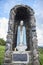 Statue of the Virgin Mary with many rosaries and protected in a stone niche