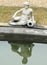 Statue of a young man sitting in front of the water