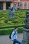 Statues of French garden of the Dobris Chateau. Tourist on background of the Maze of bushes.