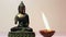 Statuette of Buddha and a burning candle.