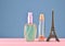 A statuette of the Eiffel Tower, bottles of perfume on a blue pastel background, minimalist trend, space for text, beauty