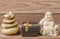 Statuette of a laughing Buddha with stones and a candle, and a gift box, on a wooden background, feng shui.