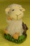 Statuette of a white sheep sitting on a chair.