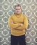 Status VIP. Portrait of a mature man wearing a polo neck sweater standing against a retro wallpaper background.
