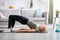 Stay at home fitness. Strong mature woman doing half bridge yoga pose, strengthening her abs muscles indoors, copy space