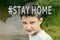 Stay home and quarantine concept. A portrait of a 10 year old boy outdoors with emotional face and a sign meaning not to go