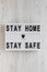 `Stay home stay safe` words on a lightbox on a white wooden background, top view. Overhead, from above, flat lay