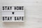 `Stay home stay safe` words on a lightbox on a white wooden background, top view. Overhead, from above, flat lay. Space for text