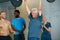 Stay hungry. a senior man lifting weights while a group of people in the background watch on.