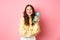 Stay hydrated. Smiling healthy girl holding water bottle with lemon and looking cheerful at camera, standing against