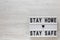 `stay safe` words on a lightbox on a white wooden surface, top view. Overhead, from above, flat lay. Space for text