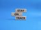 Stay on track symbol. Wooden blocks with words Stay on track. Beautiful blue background. Business and Stay on track concept