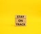 Stay on track symbol. Wooden blocks with words Stay on track. Beautiful yellow background. Business and Stay on track conc