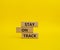 Stay on track symbol. Wooden blocks with words Stay on track. Beautiful yellow background. Business and Stay on track conc